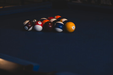 American billiards game setup with mixed balls. Close-up of colorful pool balls before the break shot. Mixed pool balls arranged on a blue billiard table.
