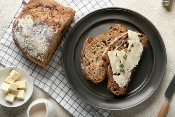 Slices of fresh bread with butter, thyme and jug of cream on light background