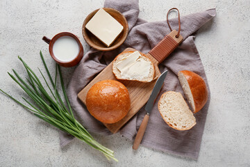 Sliced bread with butter, green onion and cup of milk on light background