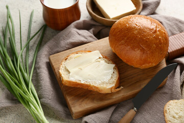 Sliced bread with butter, green onion and cup of milk on light background