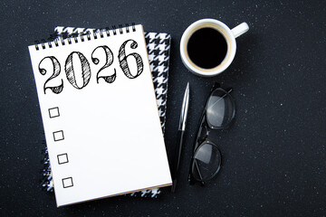 New year goals 2026 on desk. 2026 resolutions list with notebook, plant on black table. Resolutions, plan, goals, action, checklist, idea concept. New Year 2026 resolutions, copy space