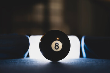 Close-Up of eight ball on blue pool table. Billiard eight ball ready for the final shot. Black eight ball on a billiard table. Focused eight ball in billiards game.