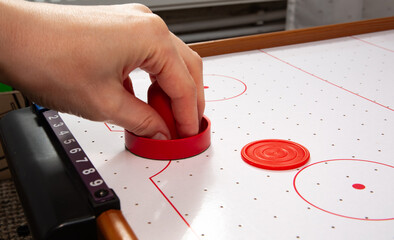 Hand ready to hit with paddle on puck. The portable table hockey includes plastic hockey paddles, a mini puck and score keepers. Hobby game background with copy space. High quality.