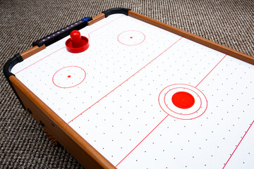 Subject shot of air hockey game table close-up. The portable table hockey includes plastic hockey paddles, a mini puck and score keepers. Hobby game background. Backdrop with copy space. High quality.