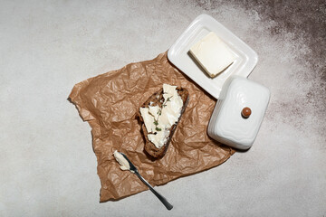 Fototapeta na wymiar Slice of fresh bread with butter and knife on grey grunge background