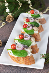 Bruschetta with herring, cream cheese, spinach and cherry tomatoes