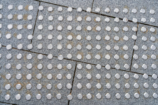 Metal tactile tiles on the granite floor.Tactile paving tiles.Designations for the visually impaired.