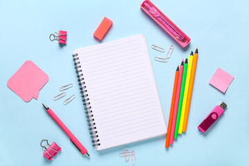 Notebook with stationery and USB flash drive on blue background