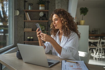 Woman working and communicating on phone from home office