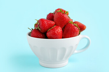 Cup with sweet strawberries on blue background