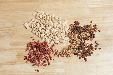 Healthy composition with organic almonds, natural raisins, freshly cracked shelled walnuts, and goji berries on wood