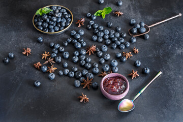  Perfectly spherical blueberries on a glossy black granite background and a brushed stainless steel spoon