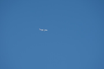 twin engined jet liner aircraft with contrails, in flight at high altitude, clear blue sky