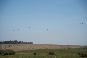 RAF Airbus C.1 A400M Atlas military transport aircraft in flight on a low-level cargo drop run, several CDS parachute deployed and descending
