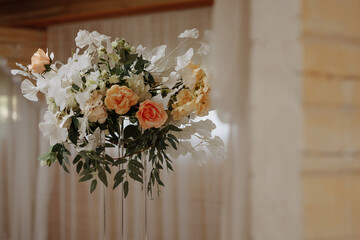Elegant white roses and hydrangeas in tall wedding centerpiece with green leaves and bokeh lights. Decor element for celebration, romance, luxury event, interior design concepts.