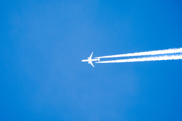 twin engined jet liner aircraft with contrails, in flight at high altitude, clear blue sky