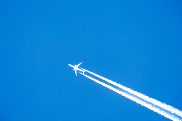 twin engined jet liner aircraft with contrails, in flight at high altitude, clear blue sky