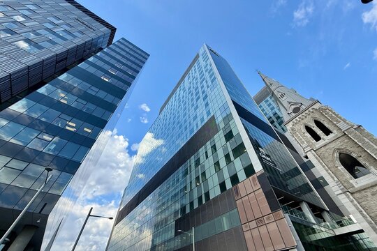 Montreal, Canada - October 07, 2025: Church surrounded by modern glass buildings in the Aut Ville-Marie district.