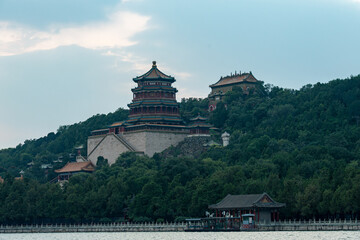 The Tower of Buddhist Incense at the Summer Palace rises above Kunming Lake, surrounded by lush hills. This wide view highlights the imperial architecture and grand scale of the park