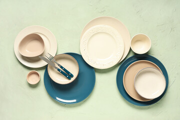 Different clean plates with silver cutlery on green background