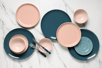 Different clean plates with silver cutlery on white background