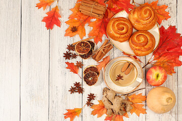 Cinnamon rolls with hot autumn drink, coffee glace and autumn fallen leaves, star anise, ginger and cinnamon on marble table, banner for display, autumn greeting concept, mockup for menu.