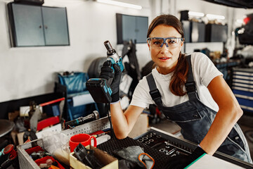 A skilled female mechanic poses confidently in a busy auto shop, showcasing her expertise and dedication