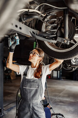 A highly skilled woman mechanic diligently performing maintenance on a vehicle within a garage environment