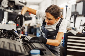 A skilled female mechanic using power tools in an auto repair shop, showcasing professionalism and expertise.