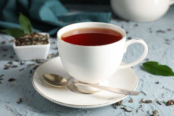 Cup of tasty black tea on blue grunge background, closeup