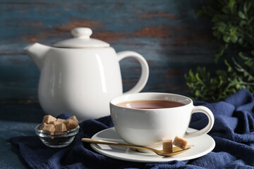 Composition with teapot and cup of black tea on blue grunge background, closeup