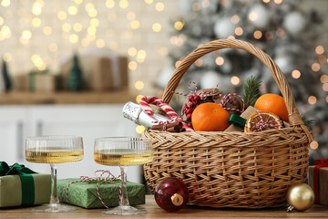 Gift basket with products and decor on wooden table in Christmas decorated room