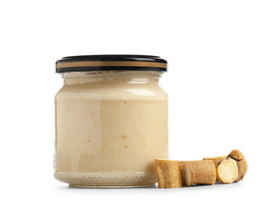 Jar of horseradish sauce with root on white background
