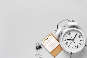 Calendar with alarm clock and binders on grey background