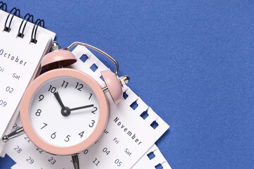 Calendar with alarm clock on blue background