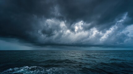 Obraz premium Thick dark clouds loom over the vast ocean creating a dramatic and foreboding atmosphere at twilight. The water reflects the somber mood of the approaching storm.