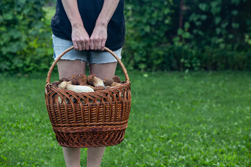 Cute girl holding a basket of porcini mushrooms