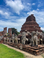Old Buddhist temple with lion sculptures ruins in a green park landscape in Ayutthaya, Thailand