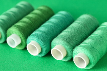 Spools of thread on green background, closeup