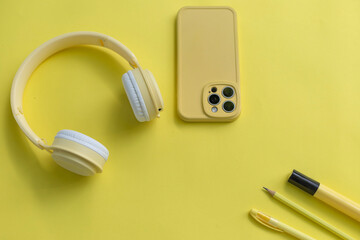 Creative monochrome flat lay with yellow headphones yellow phone yellow pencil yellow pen and...