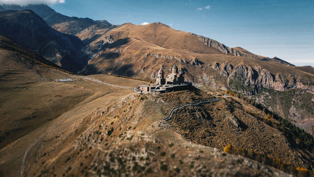 Gergeti Trinity Church on a mountain ridge in the Caucasus Mountains, Georgia. Drone view of the ancient stone monastery and high mountain landscape.