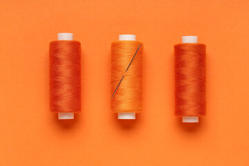 Spools of thread with needle on orange background