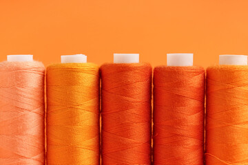 Spools of thread on orange background, closeup