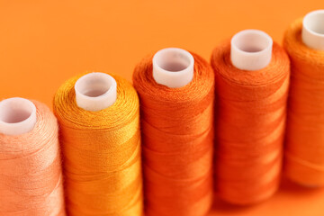 Spools of thread on orange background, closeup