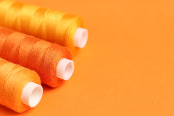Spools of thread on orange background, closeup