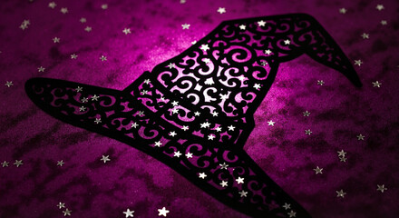 Close-up of richly decorated witch hat silhouette on velvet fabric with silver stars  