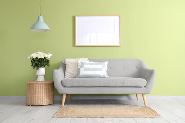 Interior of living room with sofa, basket and white roses in vase