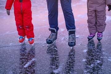 Children skate at an ice rink with an instructor. Close-up of sports shoes for skating.