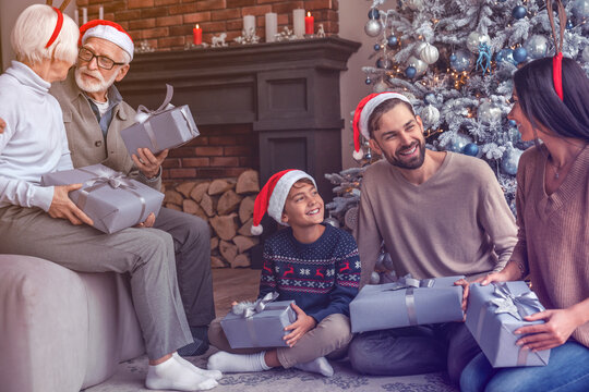Happy three generations family celebrating christmas with present boxes near Christmas tree at living room at home. Family reunion for New Year Eve. Winter holidays spirit