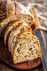 Photo of sliced ​​baked sourdough bread on cutting board on wooden table.
